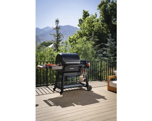 Gril à charbon de bois sur une terrasse avec vue sur le jardin.