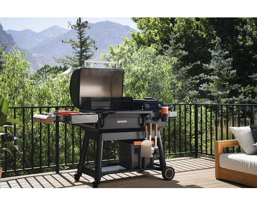 Barbecue à charbon de bois ouvert sur une terrasse avec une balustrade et vue sur un paysage verdoyant