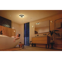 Salle de bains lumineuse avec plafonniers et femme dans la baignoire