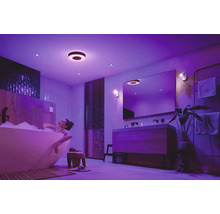 Femme se détend dans une baignoire sous des plafonniers et des spots encastrés dans une salle de bains.