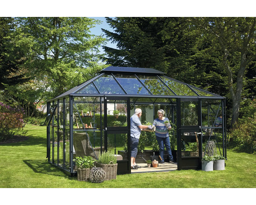 Gewächshaus mit Pflanzen und zwei Personen im Garten.