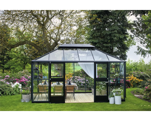 Gewächshaus mit Glastüren und Pflanzen im Garten.