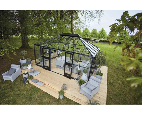 Serre avec des sièges et des plantes sur une terrasse en bois dans un jardin.