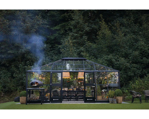 Gewächshaus mit Esstisch, Beleuchtung und Holzofen im Garten