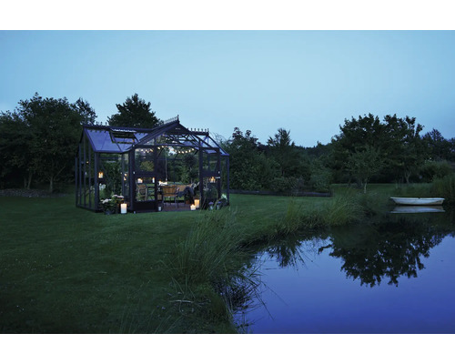 Gewächshaus mit Tisch und Stühlen im Garten am Abend