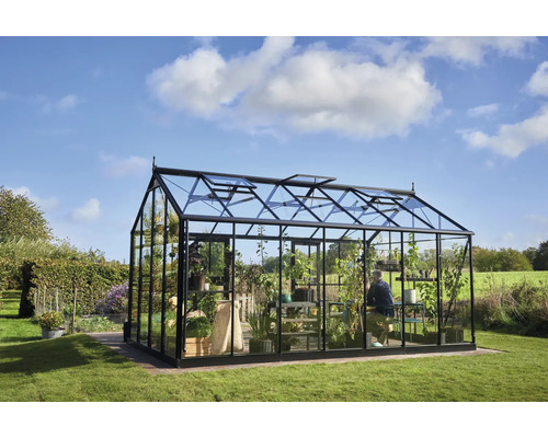 Gewächshaus mit Pflanzen und Person im Garten