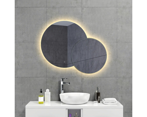 Salle de bain avec miroir rond, lavabo et robinet devant un mur gris