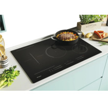 Plaque de cuisson noire avec une casserole contenant des aliments posée dessus.