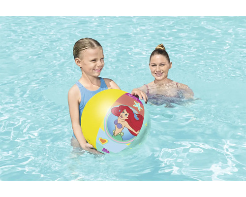 Une fille tient un ballon de plage gonflable dans une piscine