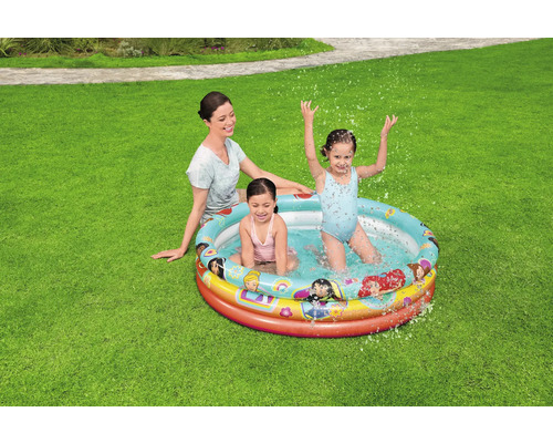 Mutter und zwei Kinder spielen in einem Planschbecken im Garten.