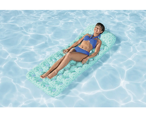 Femme se détendant sur un matelas pneumatique dans la piscine