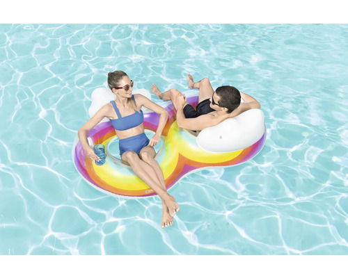 Deux personnes se détendent sur un îlot gonflable arc-en-ciel dans l''eau.