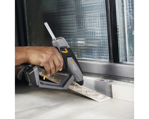 Une personne utilise un pistolet à colle chaude Steinel pour coller des carreaux.