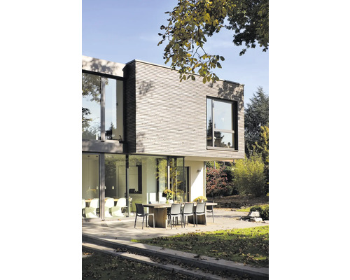 Maison moderne avec façade en bois, grandes fenêtres et terrasse avec table à manger et chaises.