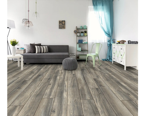 Salon lumineux avec canapé gris, fenêtre avec rideau et plancher en bois