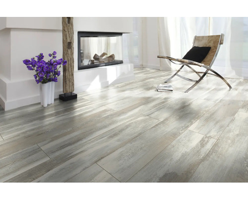 Pièce lumineuse avec cheminée, fauteuil et sol stratifié aspect bois