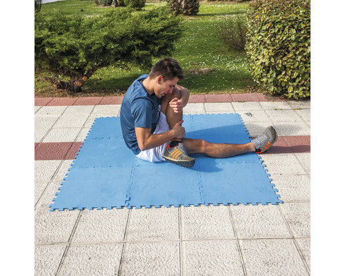 Homme s''étirant sur un tapis d''exercice bleu à l''extérieur