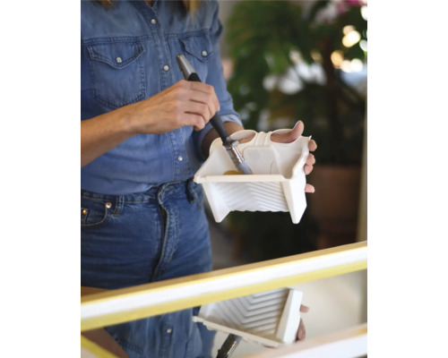 Femme trempant un pinceau dans un bac à peinture