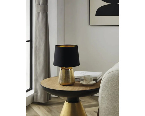Lampe de table avec abat-jour noir et pied doré sur une table d''appoint