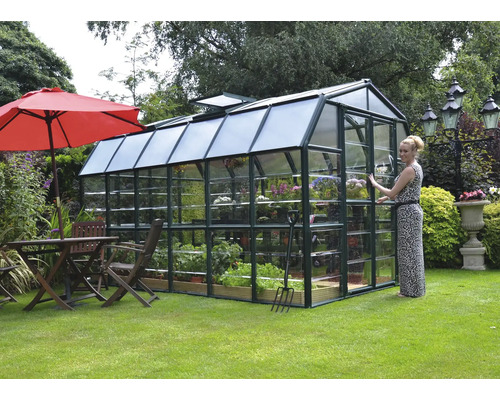 Serre avec verre, plantes et outils de jardinage dans le jardin
