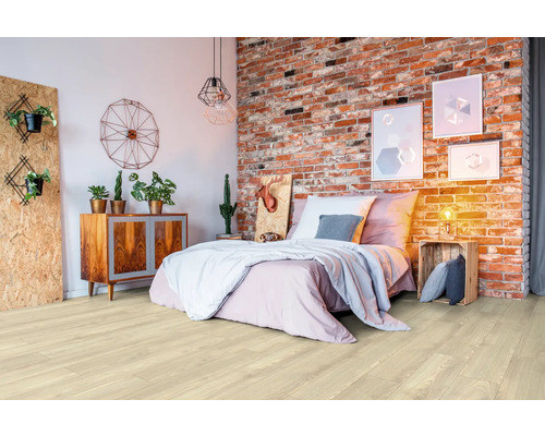 Plancher en bois clair dans une chambre avec lit et mur de briques