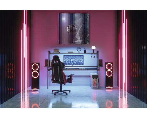 Une salle de jeux avec bureau, chaise, haut-parleurs et éclairage néon.