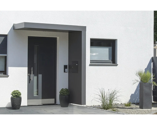 Gutta Vordach BS Plus 200 RAL 7016 anthrazitgrau 200x90 cm inkl. Briefkasten, Seitenteil rechts Wasserablauf im Seitenteil Eingangsbereich eines Hauses mit Haustür, Fenster und Bepflanzung.