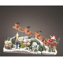 Décoration de Noël avec le Père Noël en traîneau survolant un village enneigé