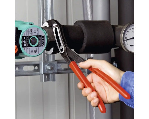 Une personne utilise une pince multiprise sur un système de chauffage.