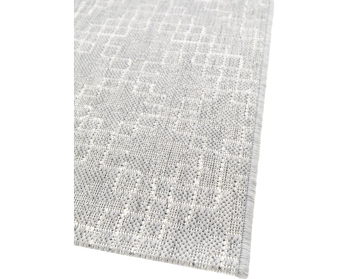 Detailansicht eines hellen Teppichs mit geometrischem Muster.