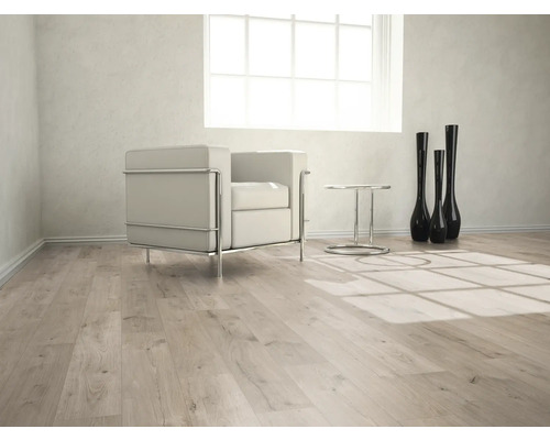 Pièce lumineuse avec sol stratifié, fauteuil, table et vases décoratifs.