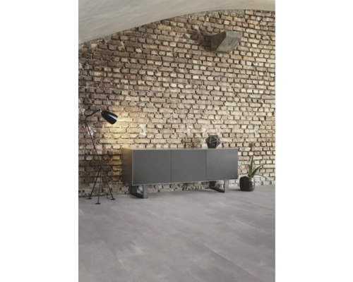Meuble gris devant un mur en briques avec lampadaire et décoration