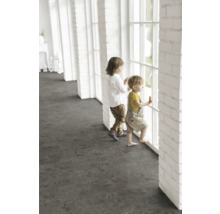 Des enfants se tiennent à une fenêtre dans une pièce lumineuse avec un revêtement de sol foncé