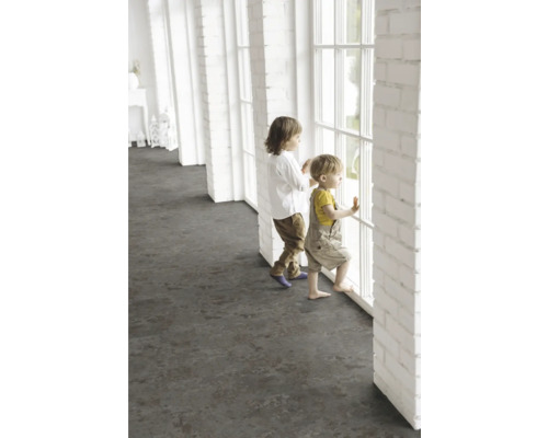 Des enfants se tiennent à une fenêtre dans une pièce lumineuse avec un revêtement de sol foncé